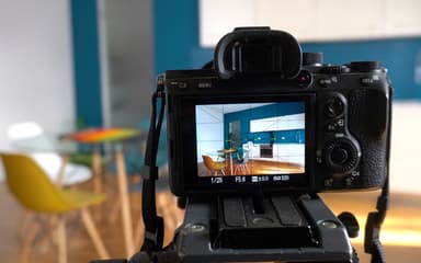 A camera on a tripod framing a kitchen and dining room through its rear screen